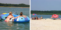 Links schwimmen zwei Personen auf aufblasbaren Schläuchen in einem See, rechts entspannen sich Menschen unter Sonnenschirmen an einem Sandstrand mit Bäumen im Hintergrund.